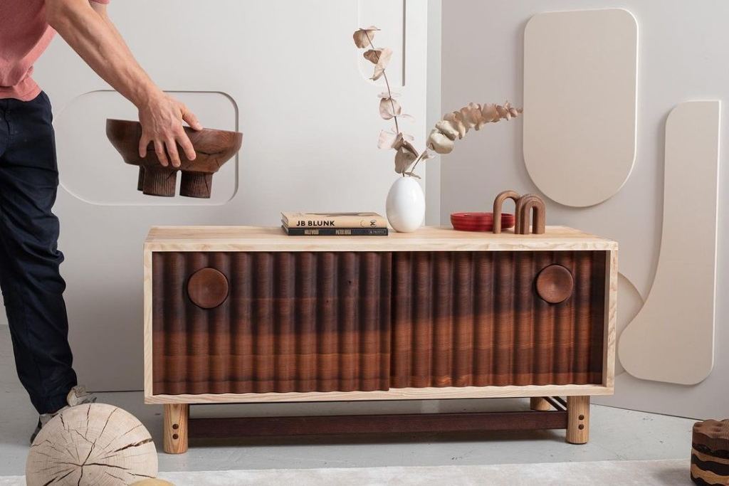 Dressoir met geprofileerde houten schuifdeuren, een hand zet er een houten schaal op
